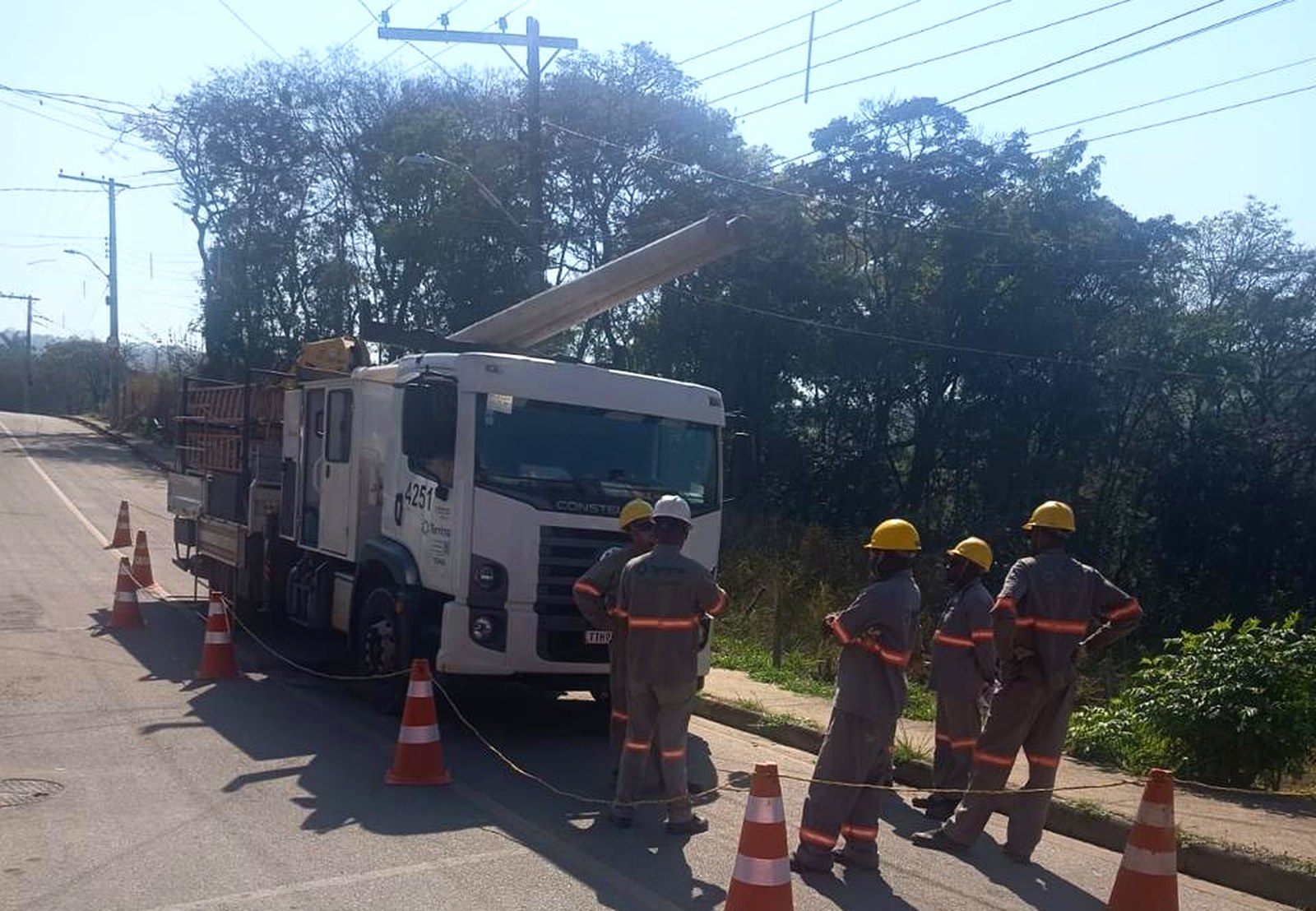 Equipe da Terrima e caminhão munck durante içamento de poste em rede de distribuição, com área isolada por cones