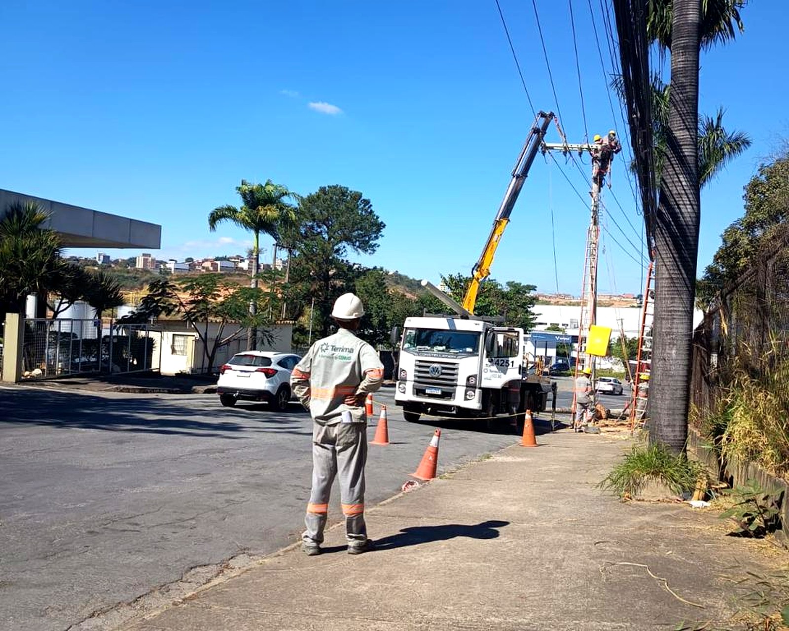 Colaborador da Terrima sinalizando a via durante serviço em poste com caminhão munck